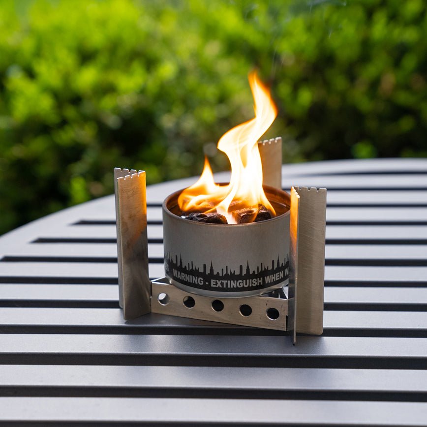 Portable fire pit with flames on a metal surface outdoors