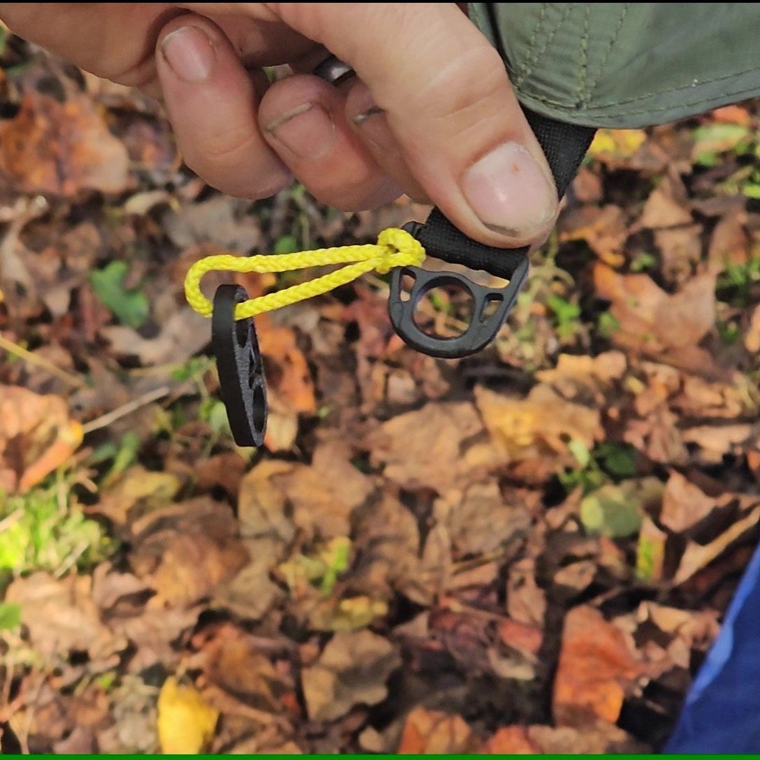 Person holding a black and yellow noose in front of a leafy background