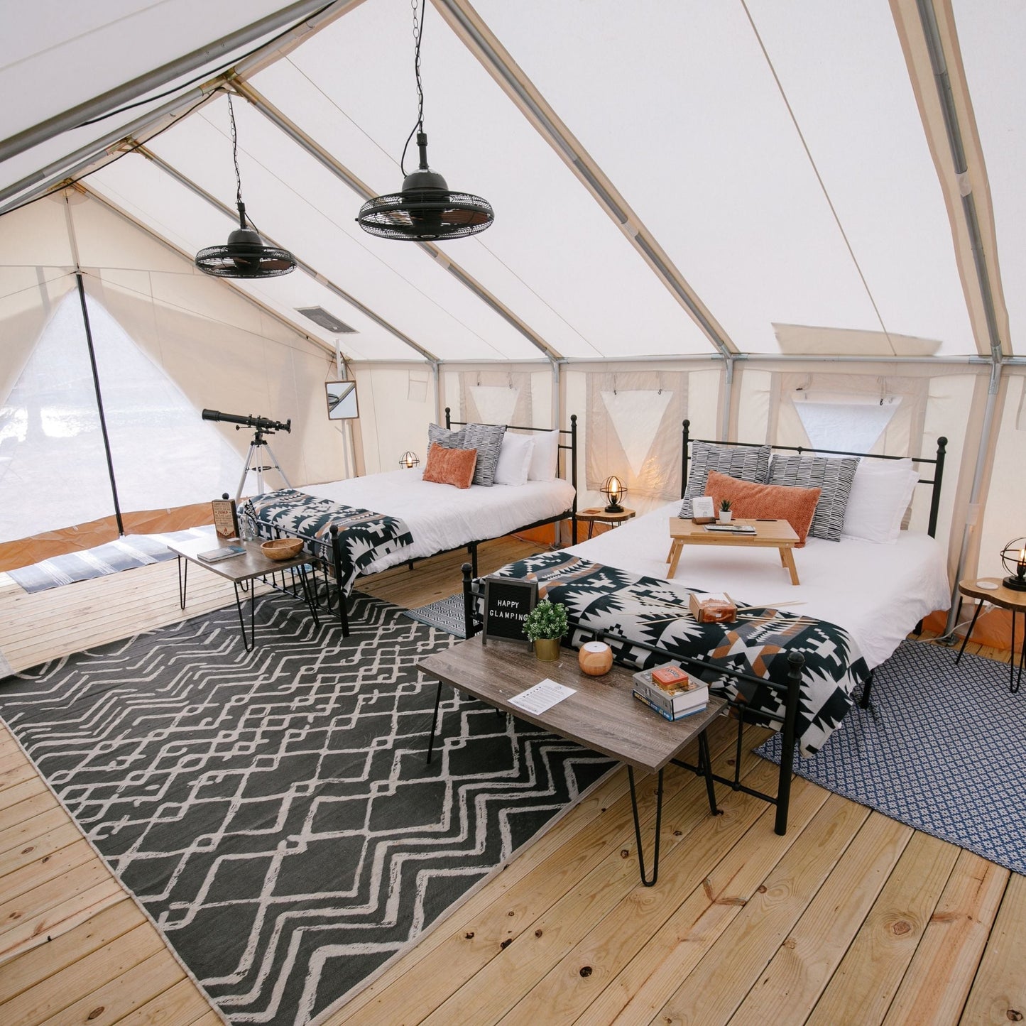 Interior of a stylish tent with wooden flooring, patterned rug, and modern decor.
