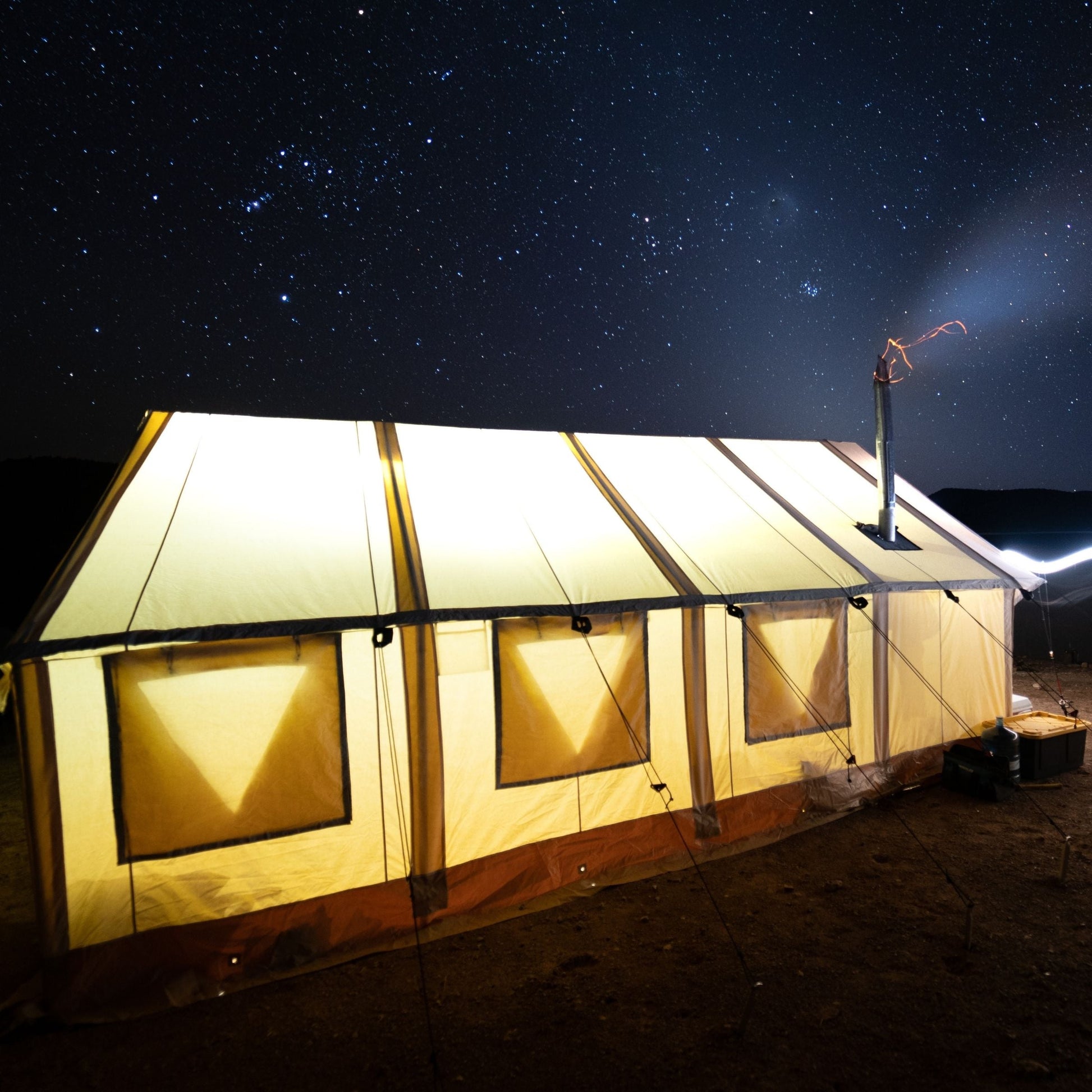 Large illuminated tent under a starry night sky