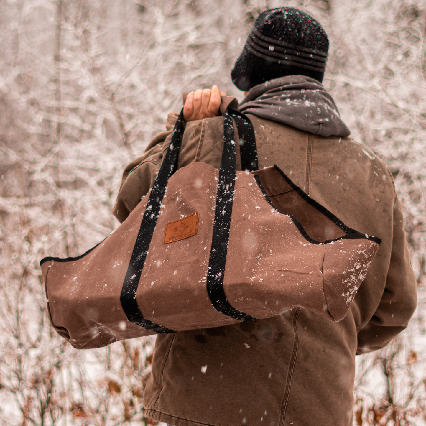 Person carrying a large brown bag with black straps through a snowy landscape