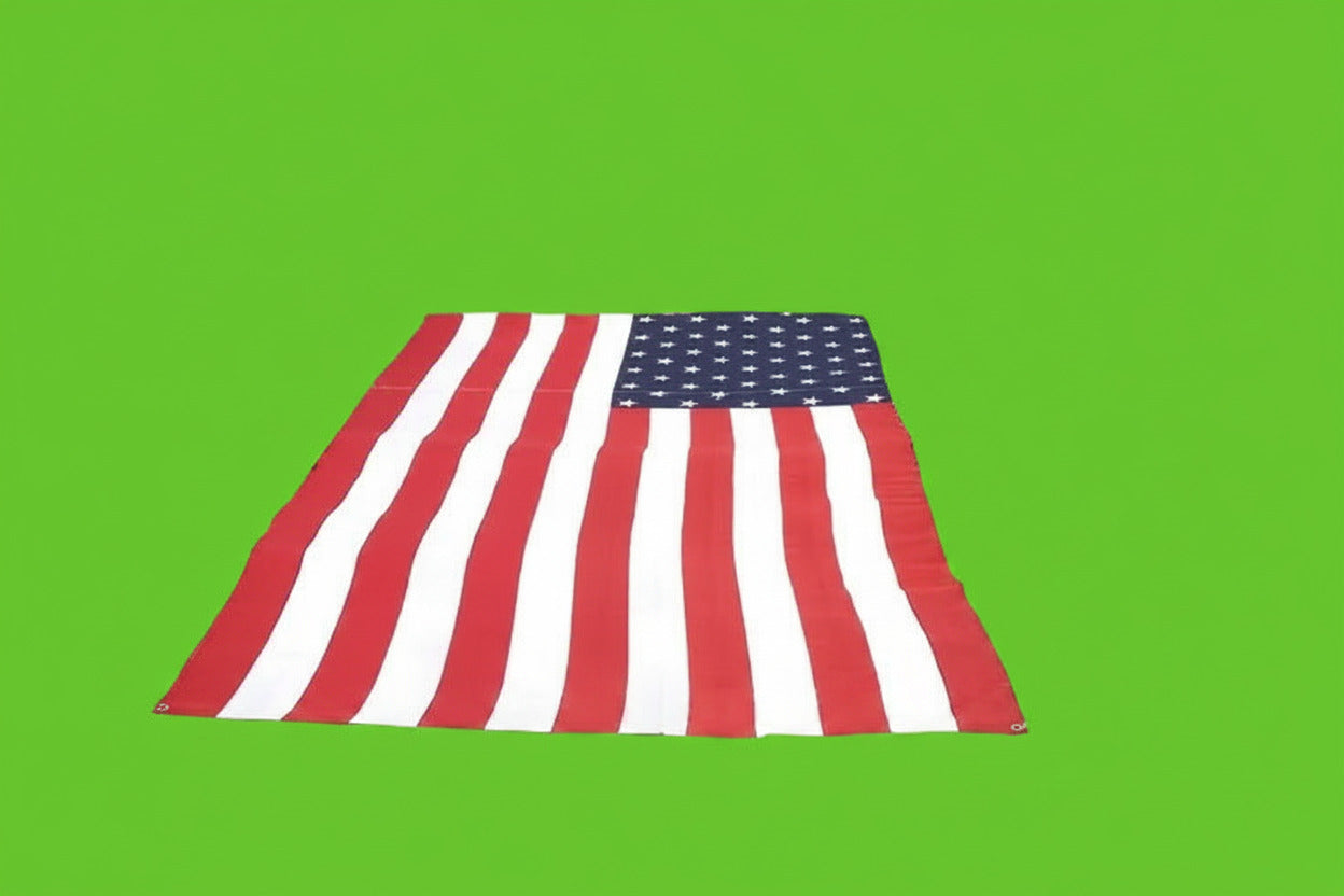 Large American flag displayed on a football field with a stadium full of spectators.