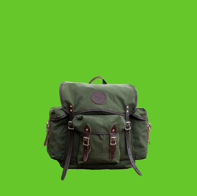 Green backpack on a rocky outcrop with a scenic view of water and cliffs.