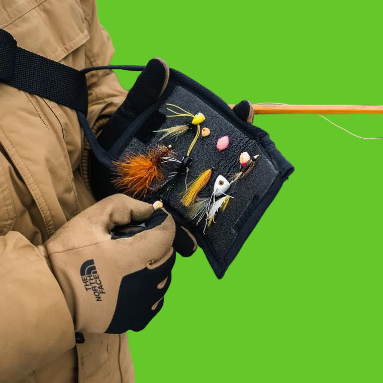 Person holding a box of fishing lures with a blurred water background