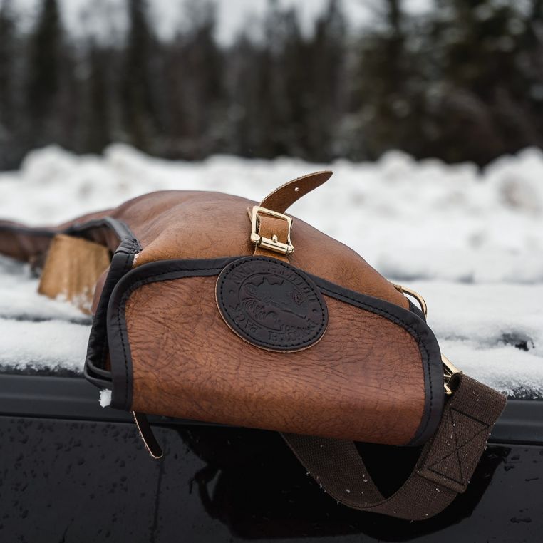 Brown leather saddle on a vehicle with a blurred snowy background