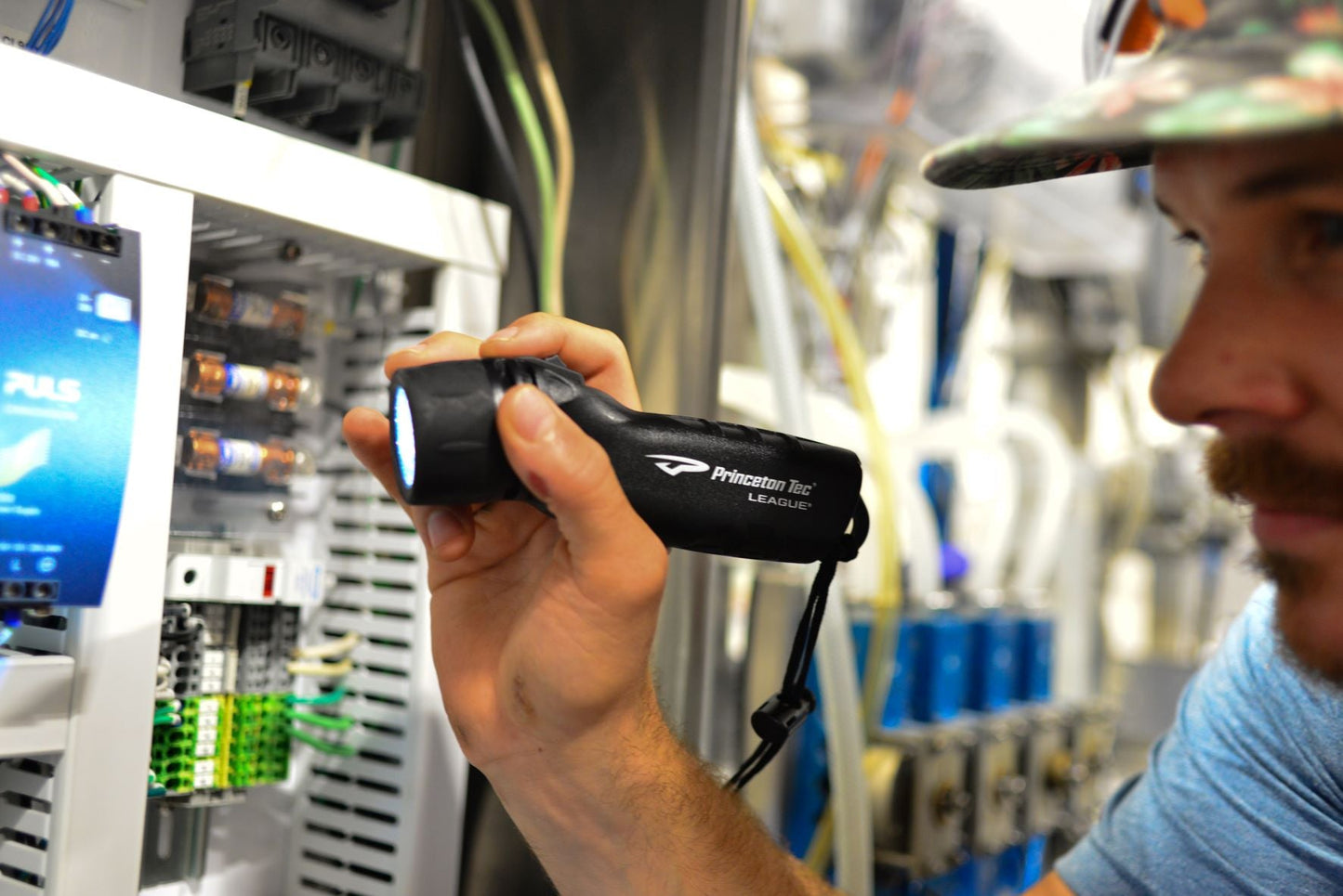 Person holding a flashlight in a technical setting with equipment and screens in the background