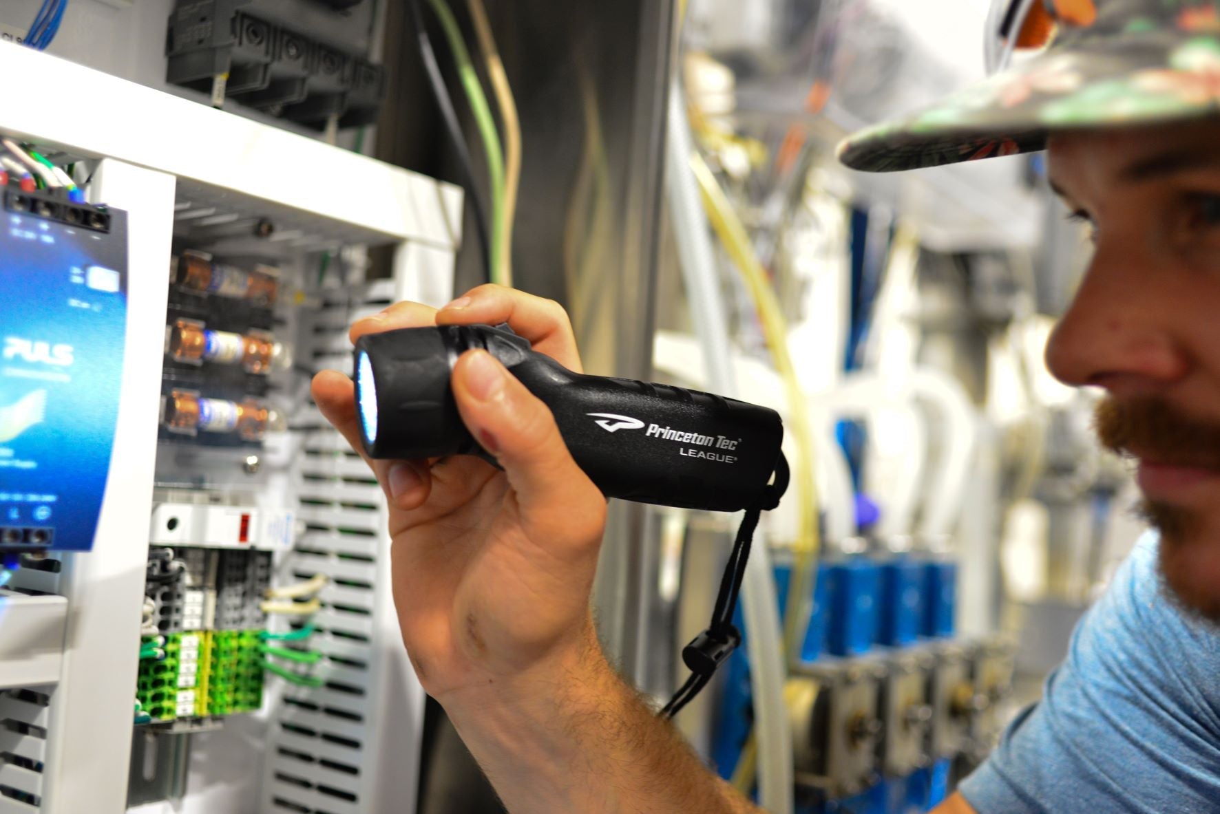Person holding a flashlight in a technical setting with equipment and screens in the background