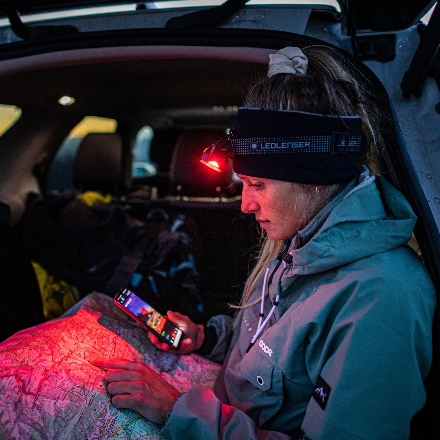 Person sitting inside a vehicle using a smartphone with a headlamp on