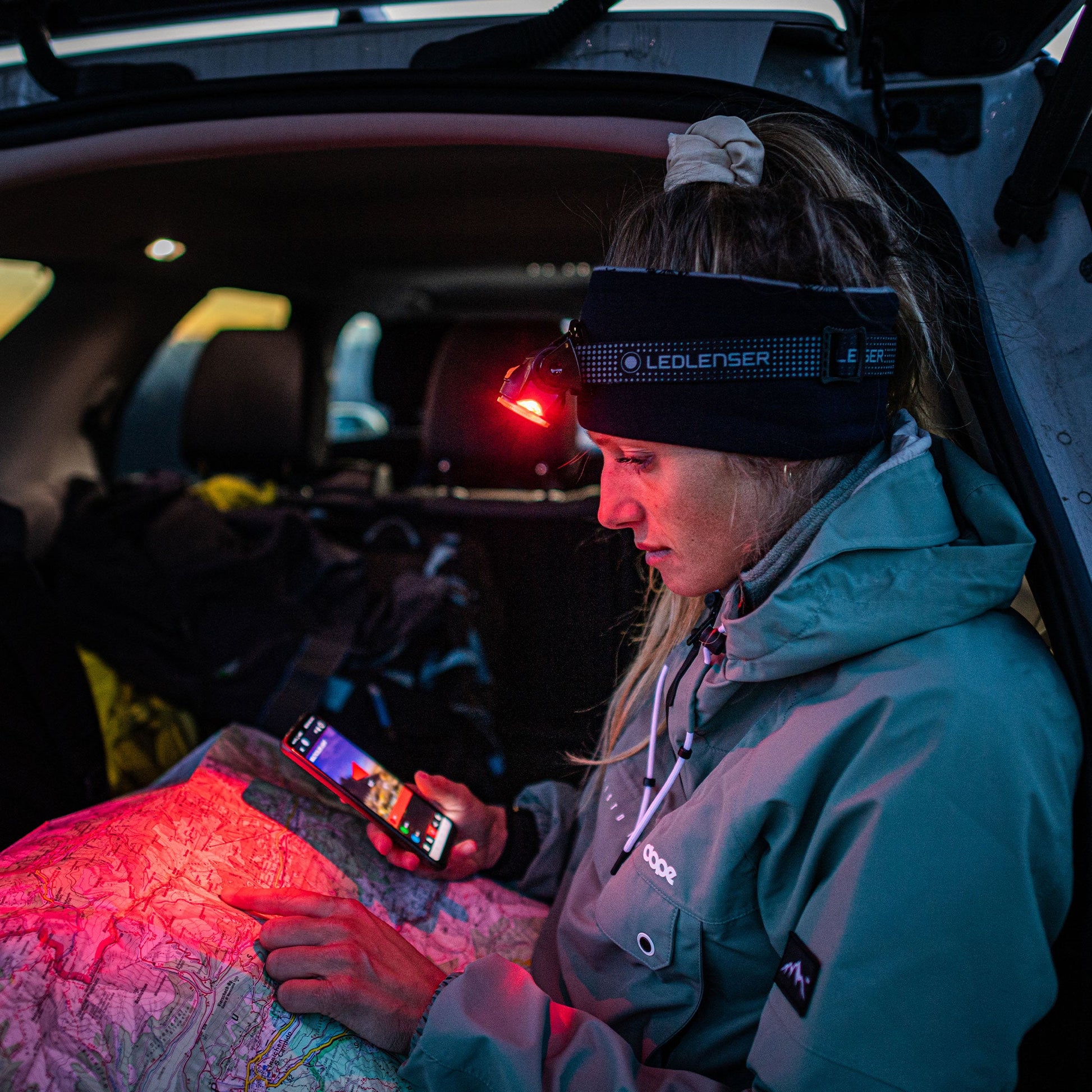 Person sitting inside a vehicle using a smartphone with a headlamp on