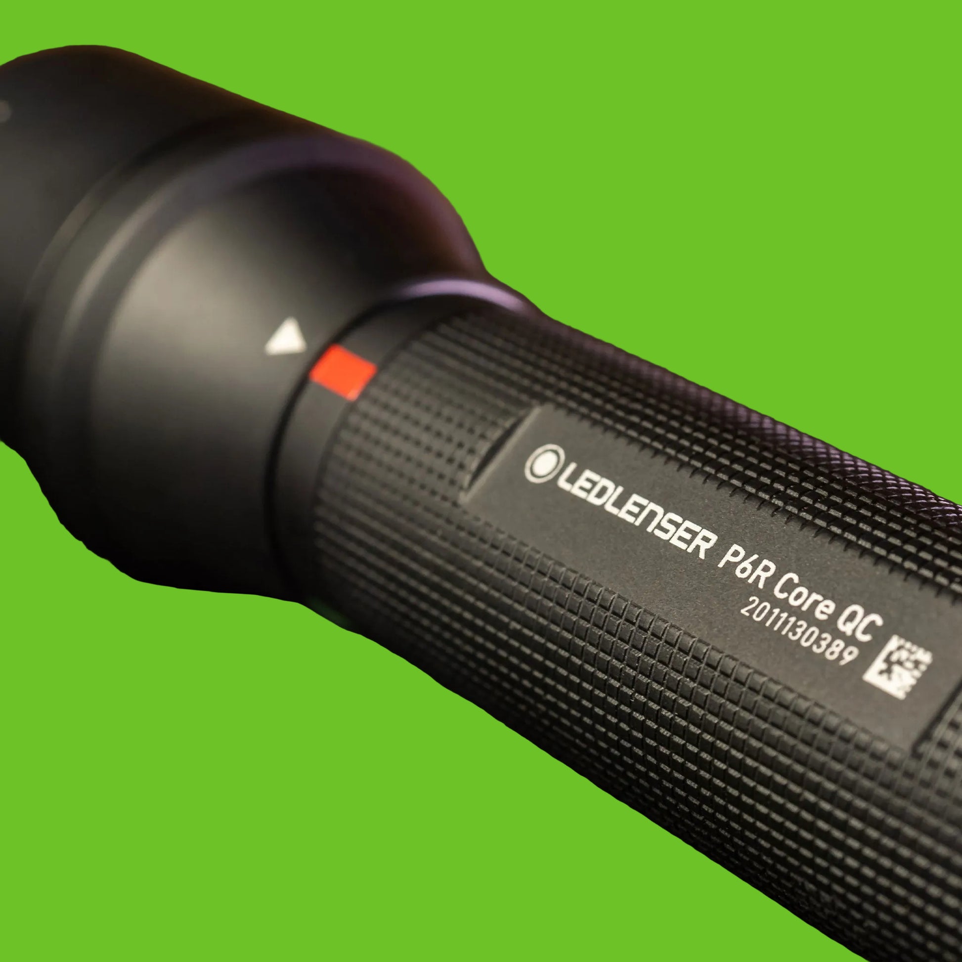 Close-up of a black LED flashlight with visible branding on a dark background