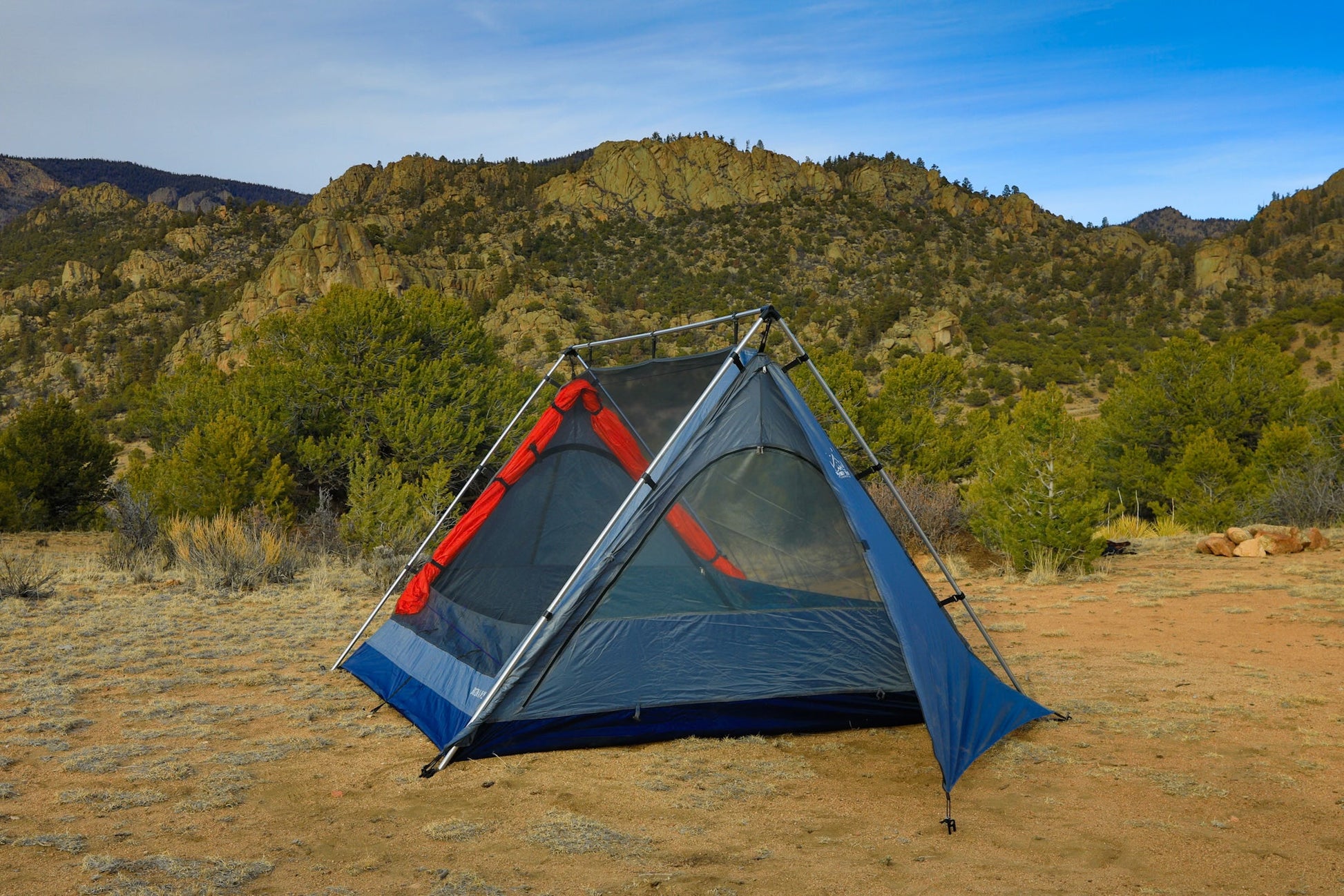 Camping tent set up in a desert landscape with mountains in the background