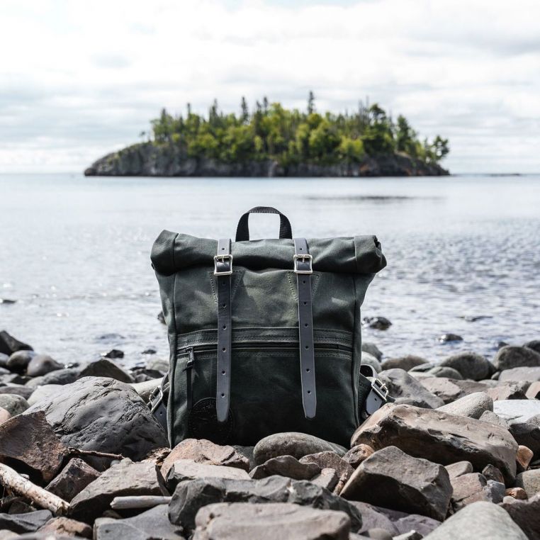 Green backpack on rocks with a lake and island in the background