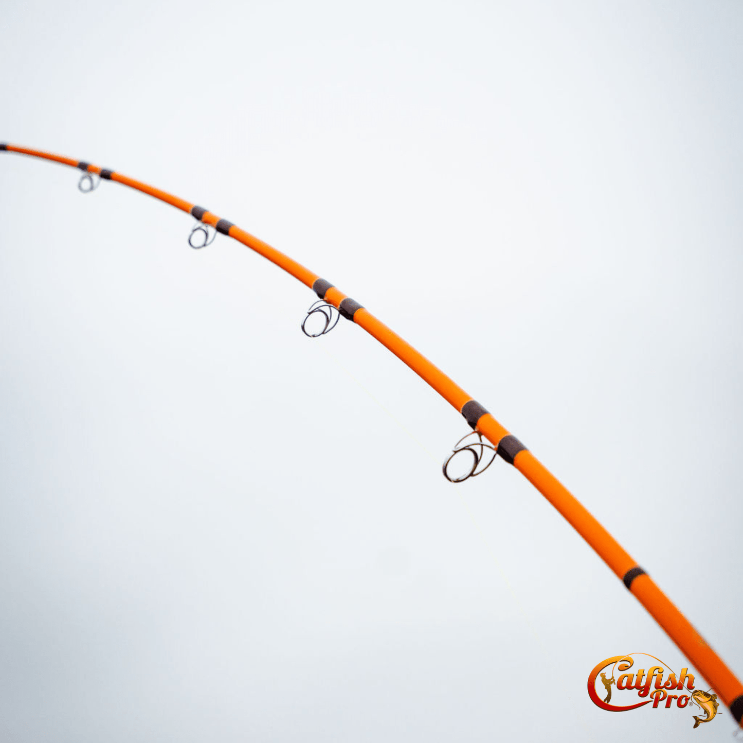 Orange fishing rod with black rings on a light gray background