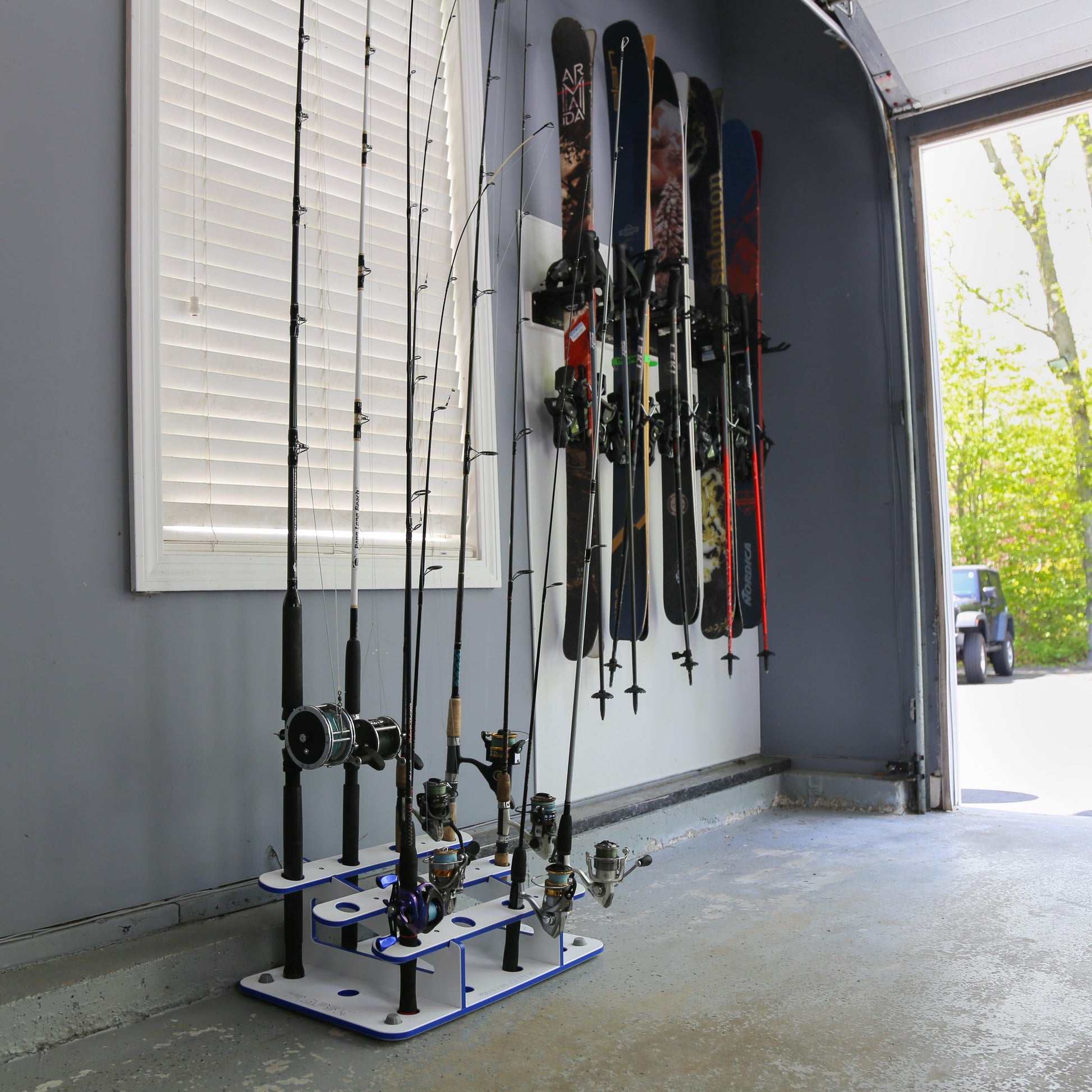 Fishing rod holder with multiple fishing rods and skis on a wall in a garage.