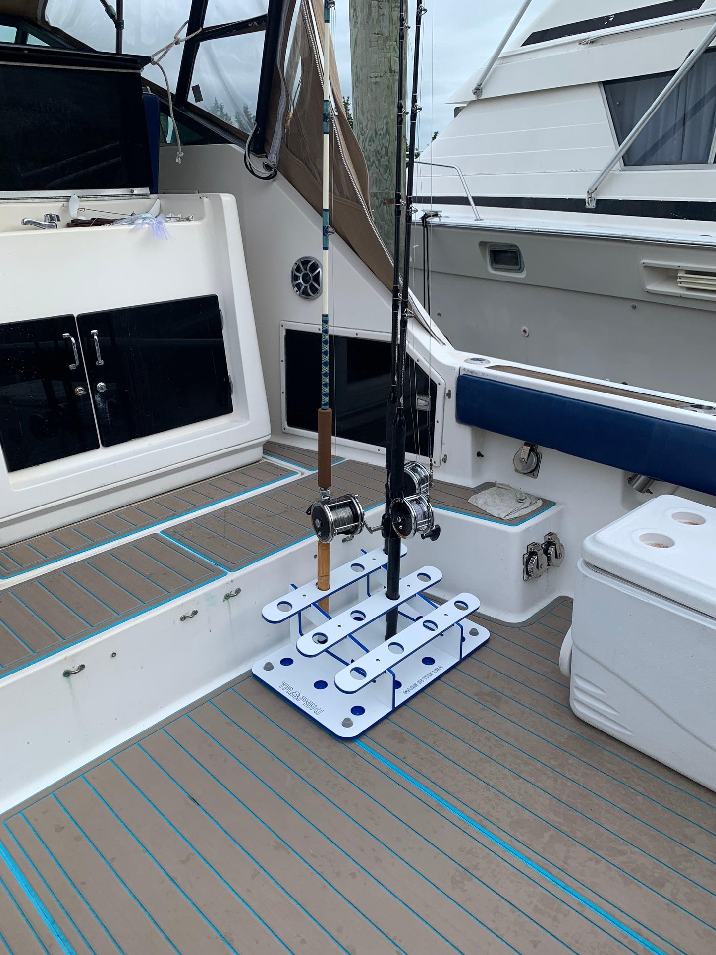 Fishing rod on a stand inside a boat cabin with white walls and blue flooring.
