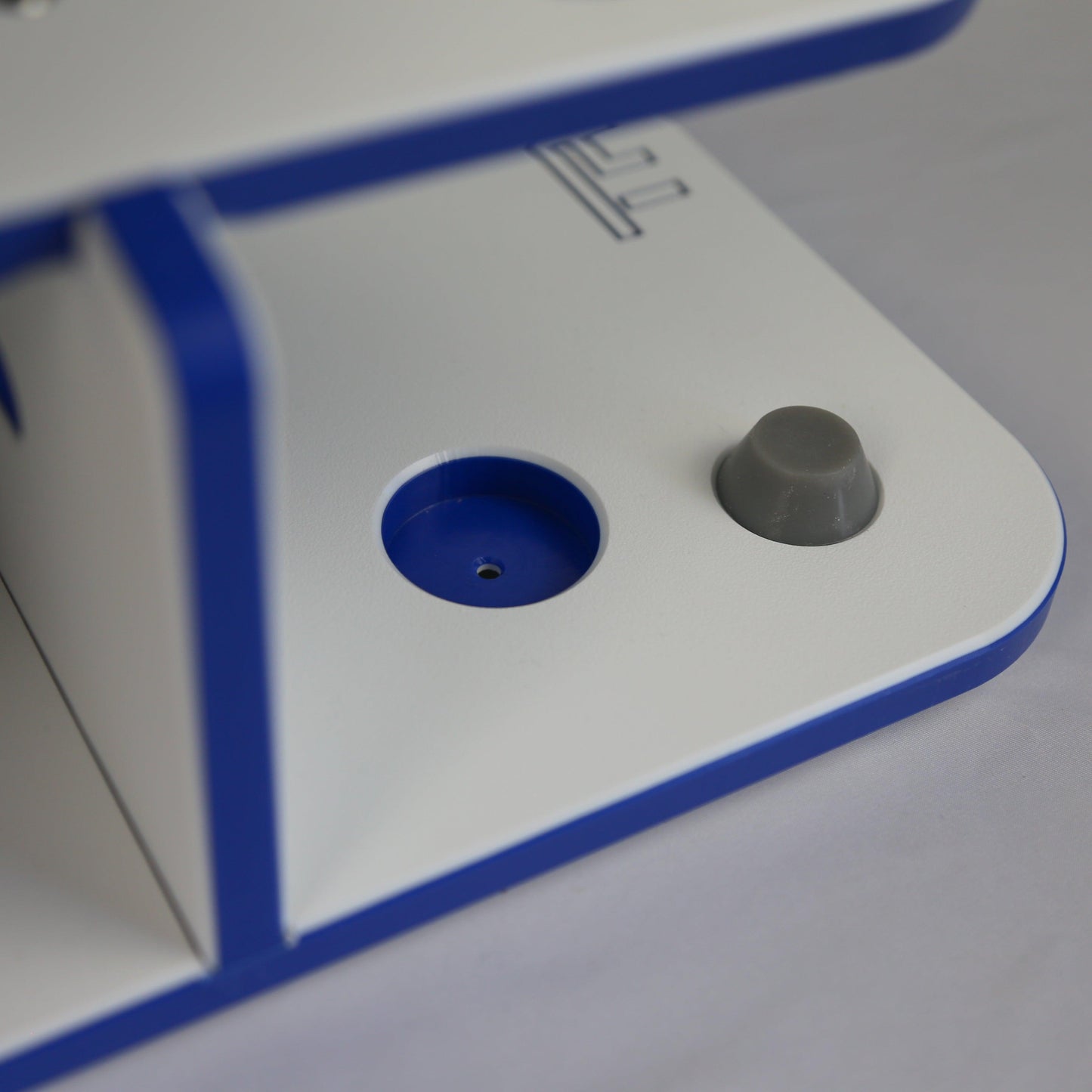Close-up of a white electronic device with blue border and gray knob on a light gray background