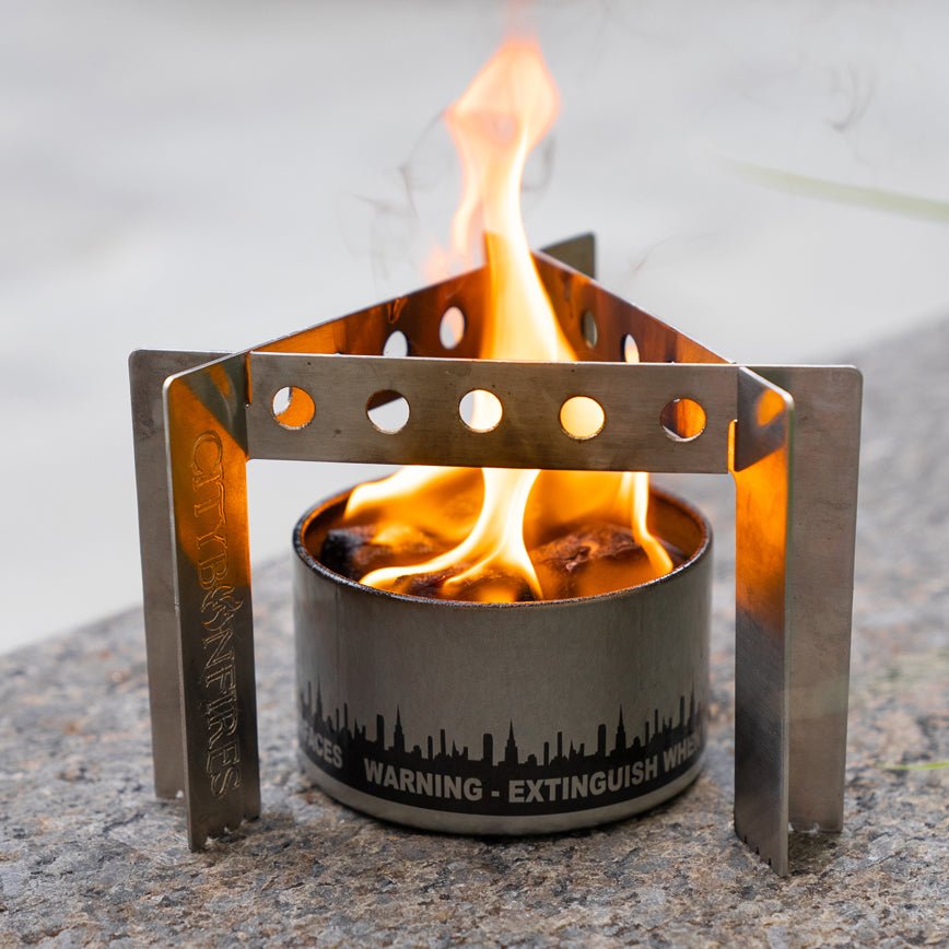 Small metal fire pit with flames on a concrete surface