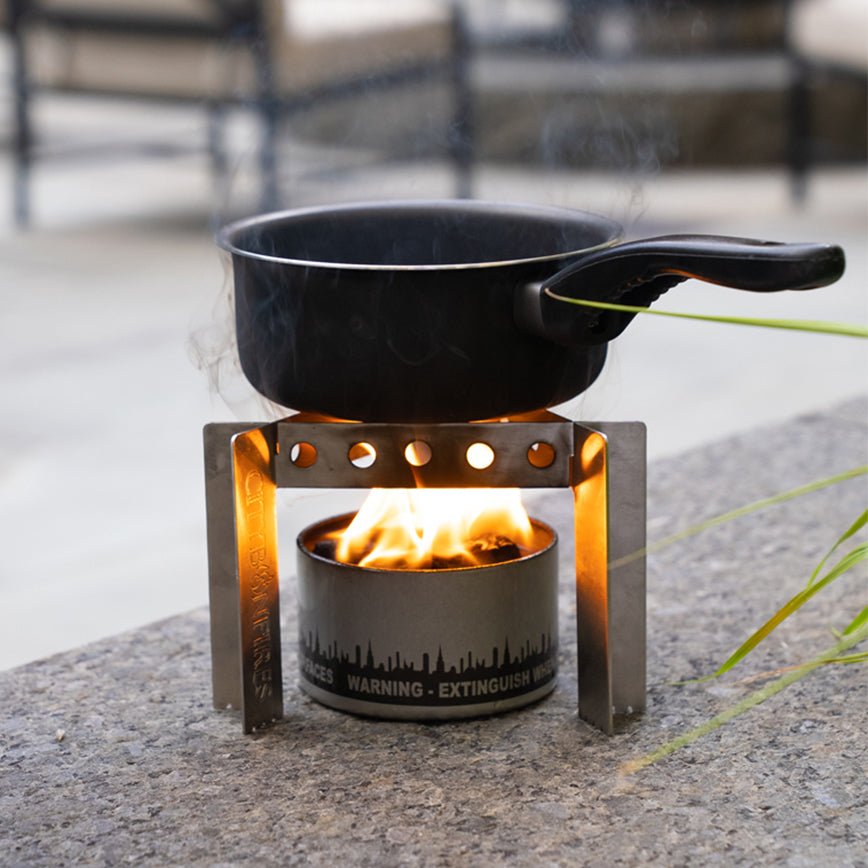 Portable stove with a pan over a flame on a concrete surface