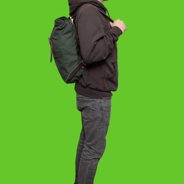 Person wearing a green backpack and dark hoodie on a white background