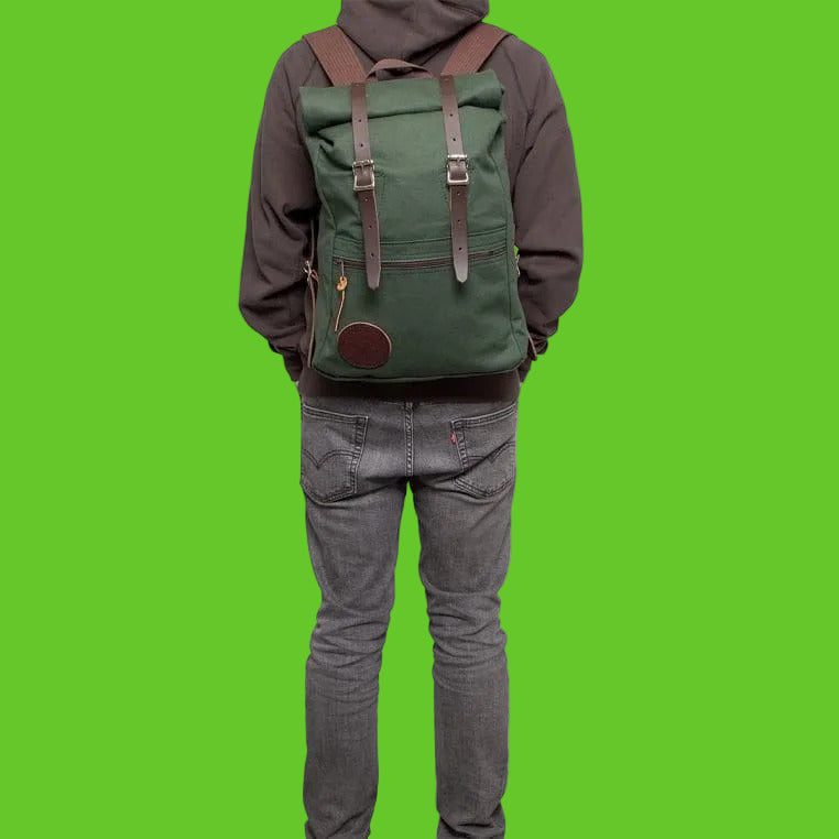 Person wearing a green backpack with brown straps on a white background