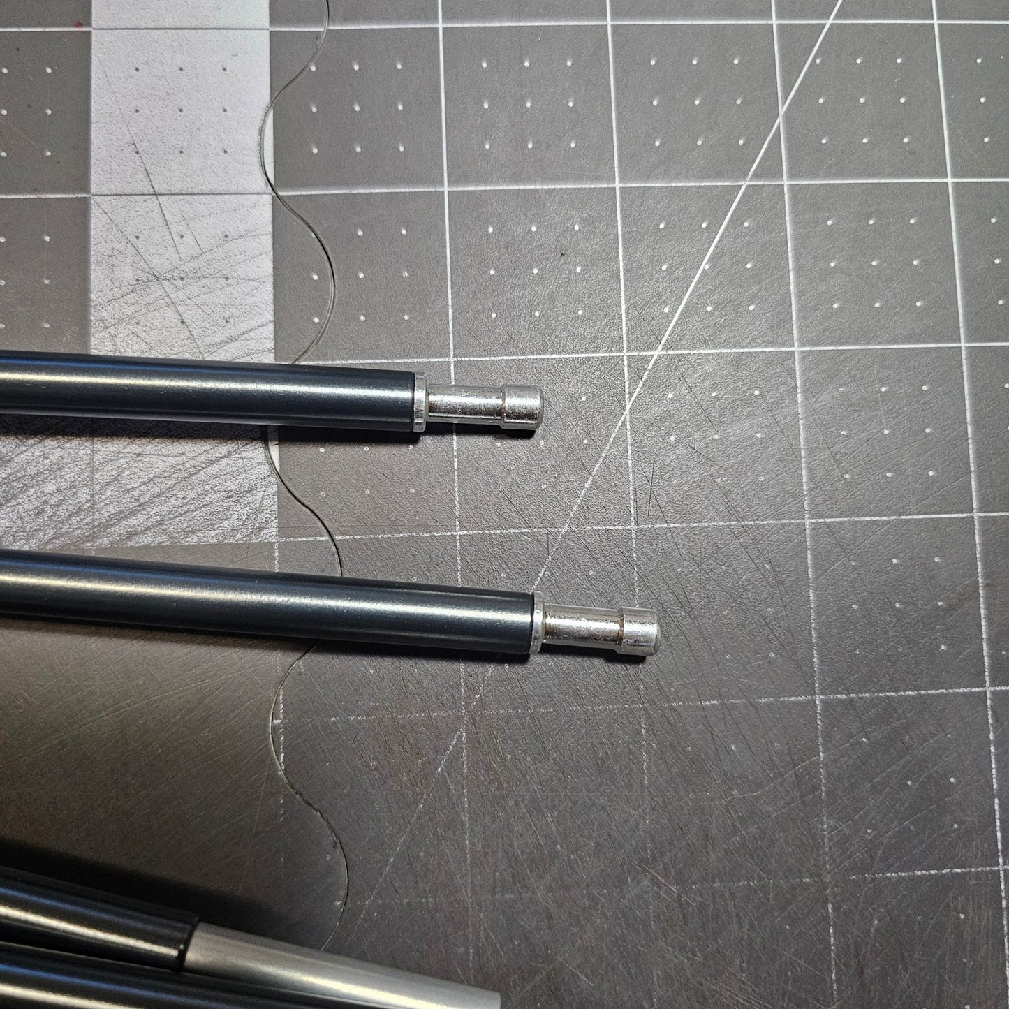 Metal rods on a gray cutting mat with grid lines