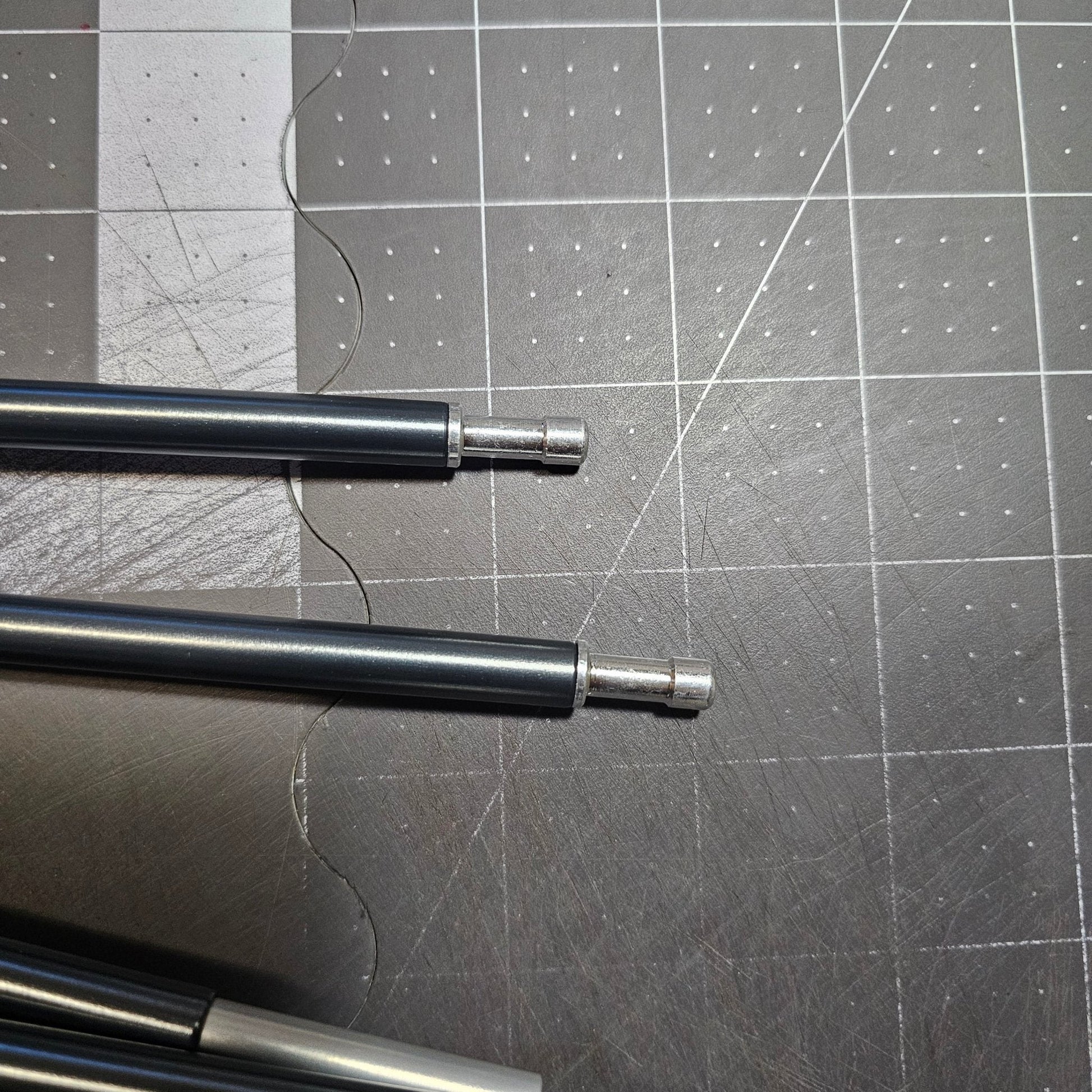 Metal rods on a gray cutting mat with grid lines